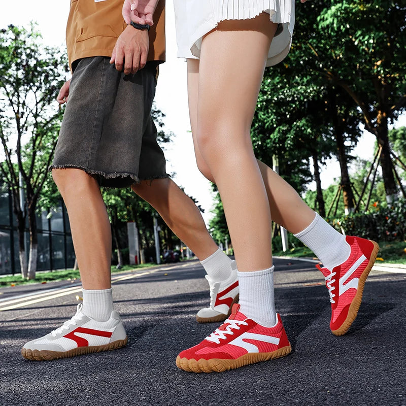 Two people wearing white and red barefoot sneakers outdoors
